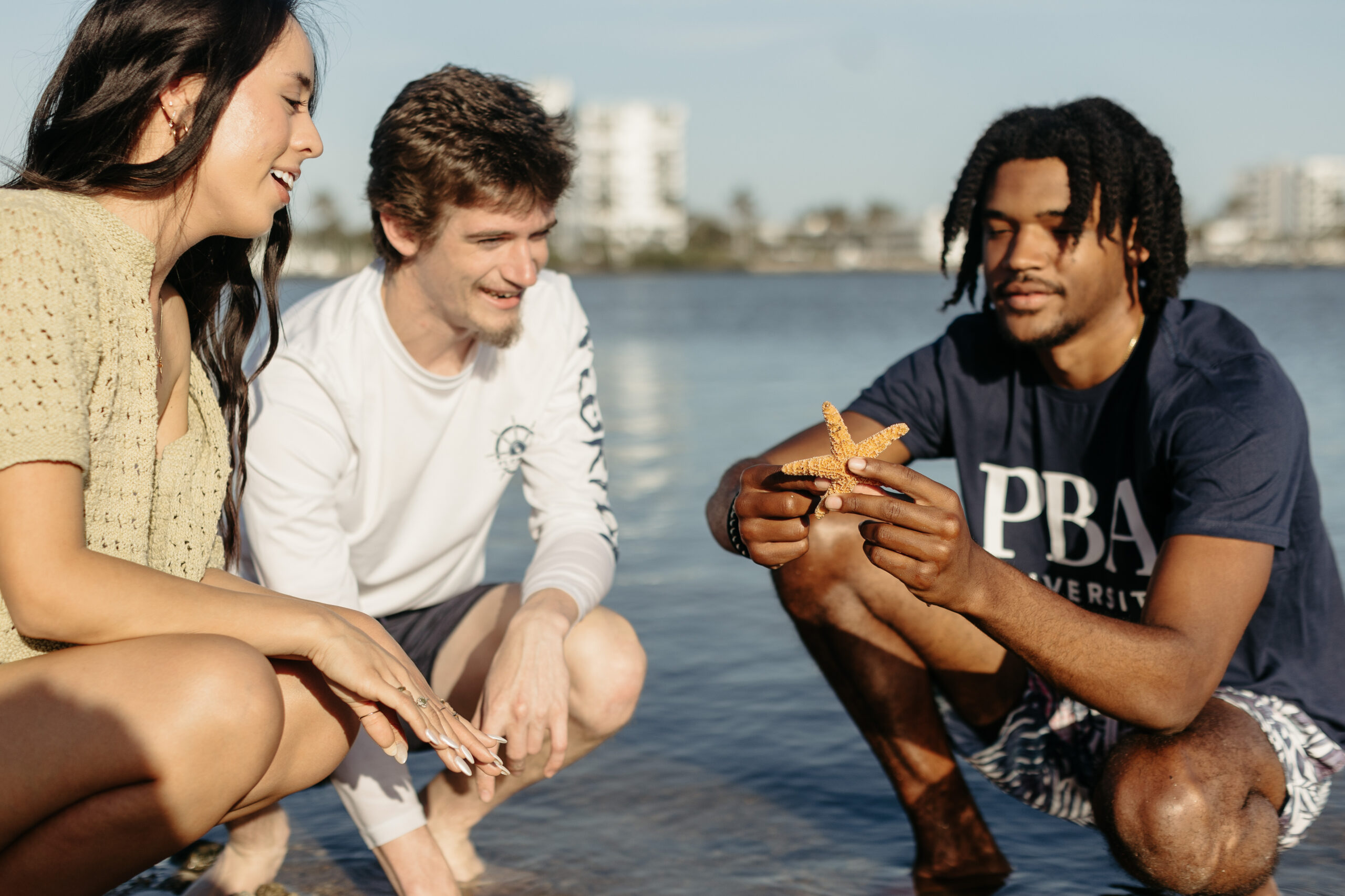 three PBA students looking at a starfish