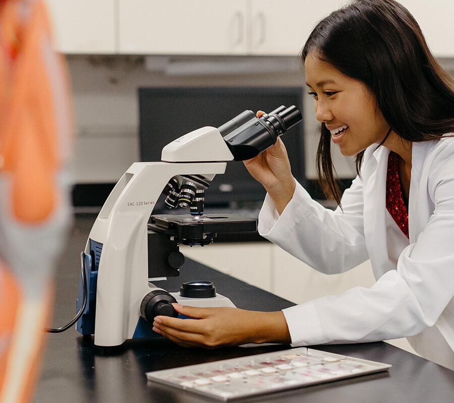 Student looks into a microscope in a laboratory session.