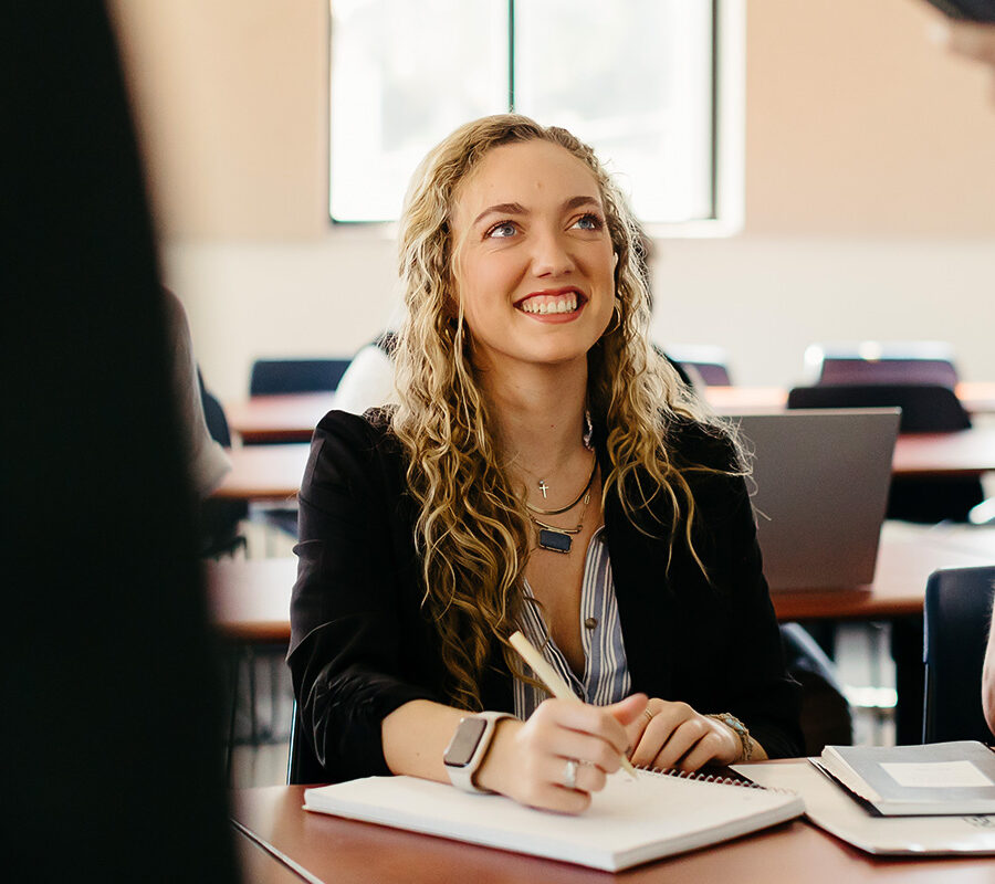 Creative writing student writes in a notebook in a classroom.