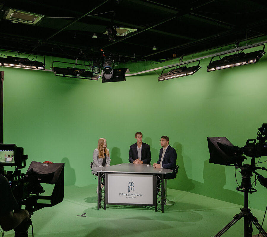 Sports broadcasting students present in front of a green screen.