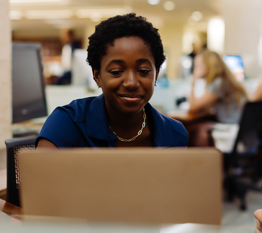 A PBA student works on a laptop in the library.