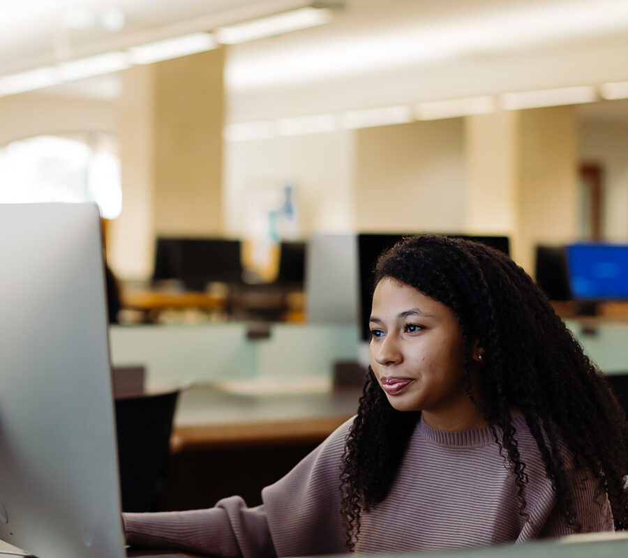 graphic arts and graphic design student uses a computer in the library.