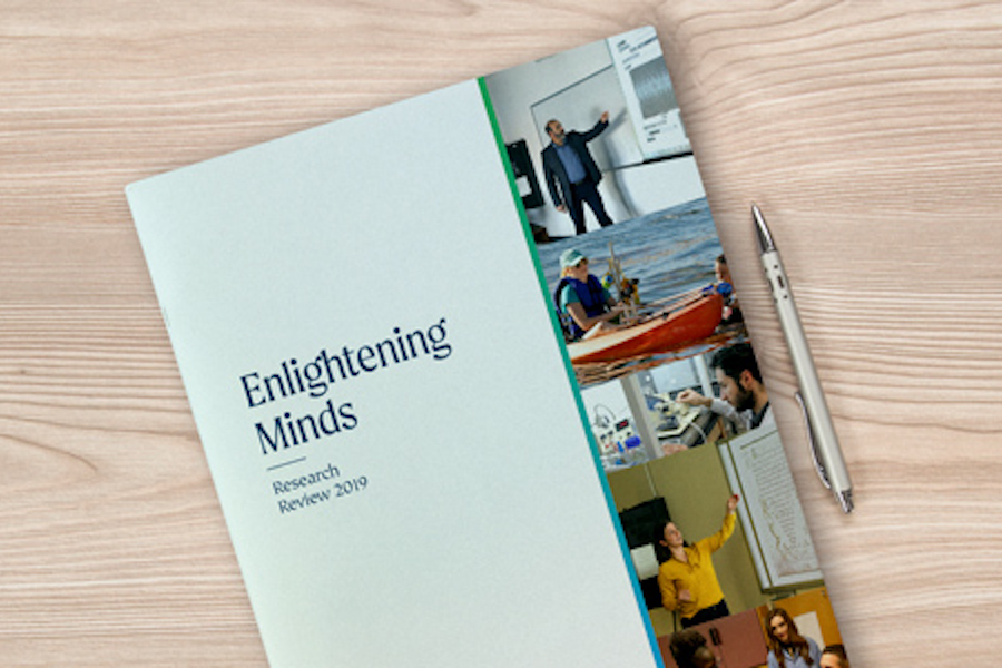 A copy of Palm Beach Atlantic University's Enlightening Minds laying on a tabletop next to a pen.