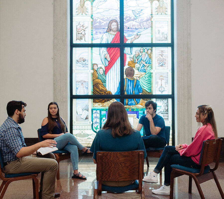 Ministry students sit in a circle and study the bible in a chapel.