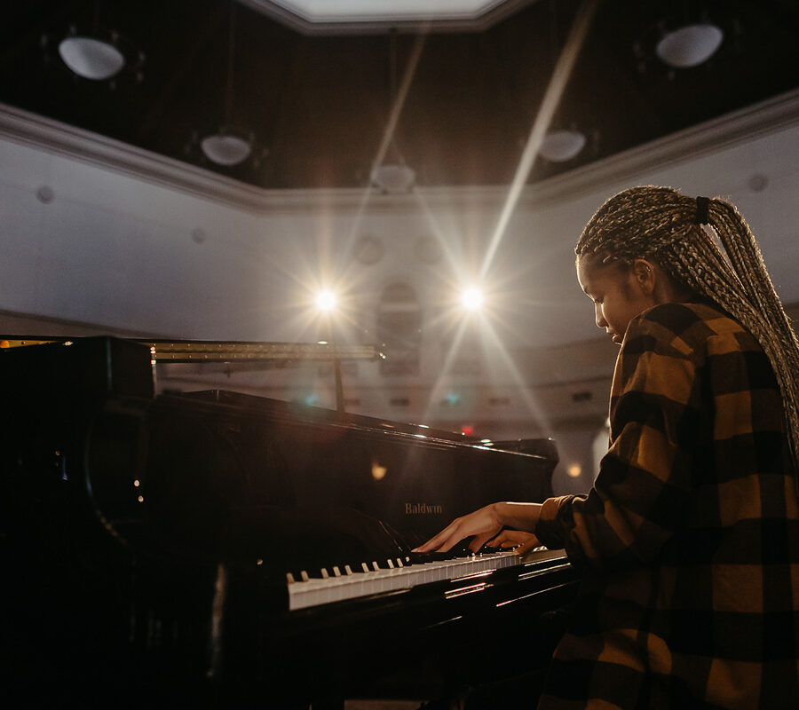 Music student plays the piano in an auditorium.