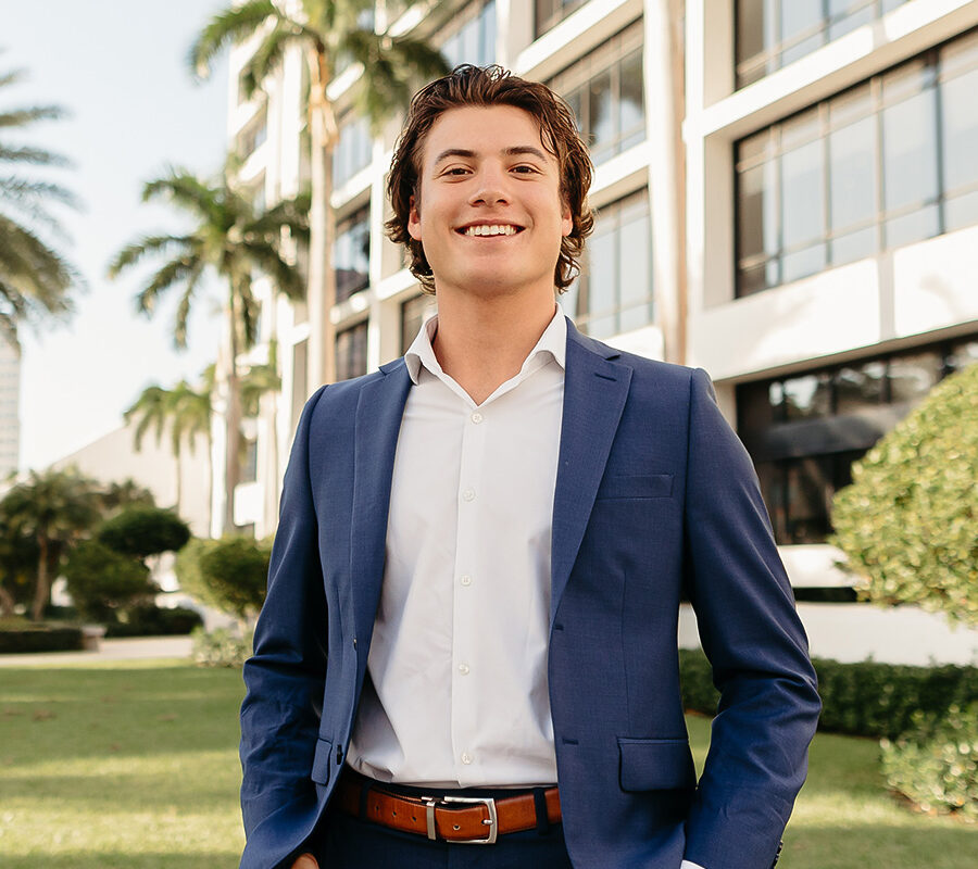 a male student standing outside of a building on campus at Palm Beach Atlantic University